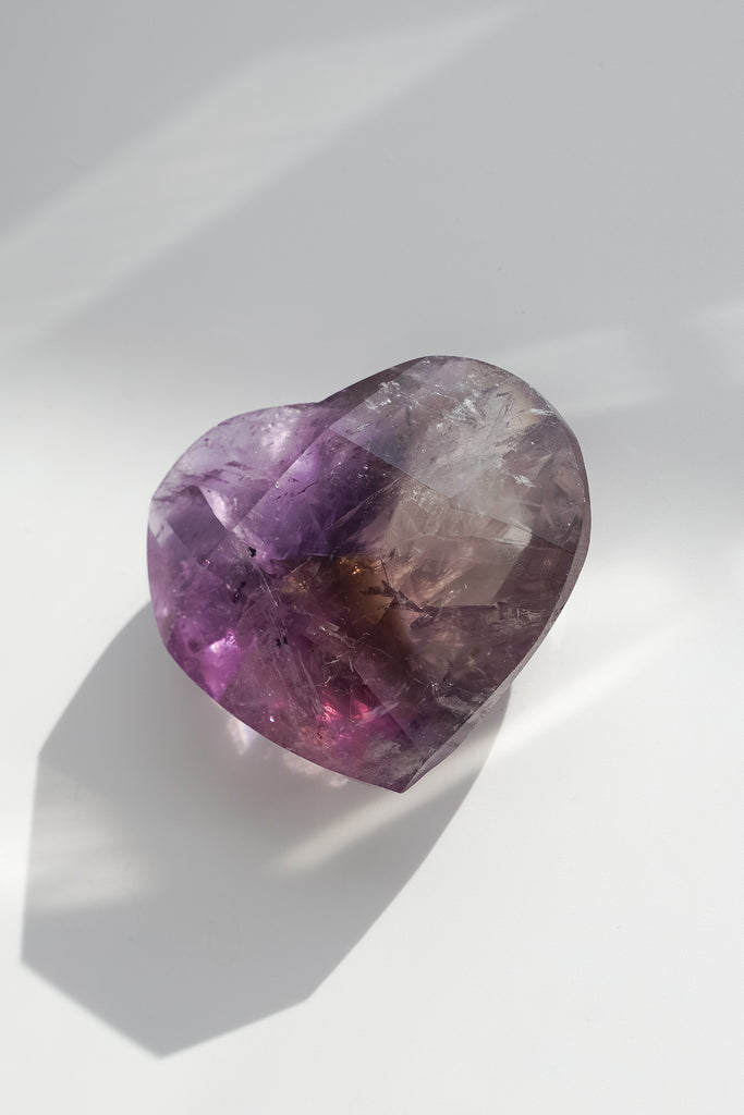 Heart-shaped purple crystal on a white background