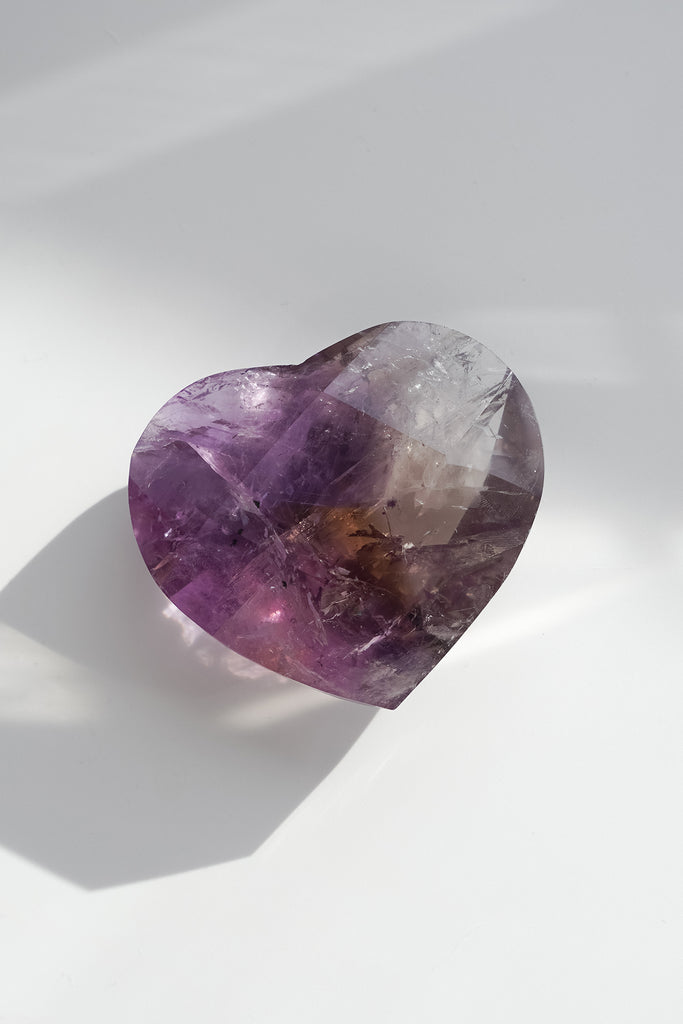 Heart-shaped purple gemstone on a white background