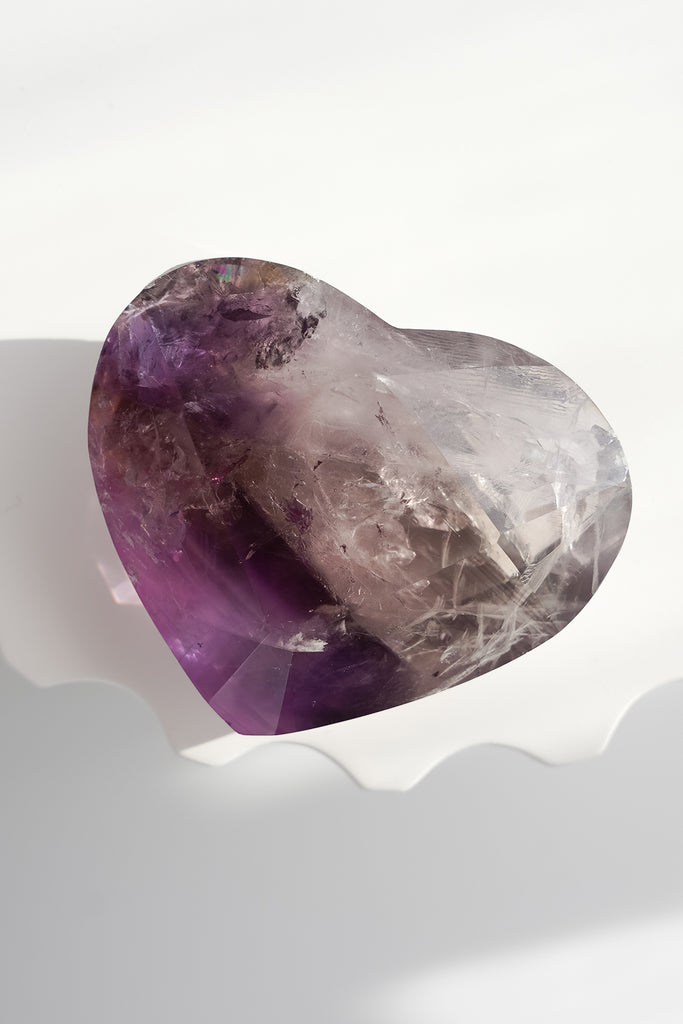 Heart-shaped amethyst crystal on a white background