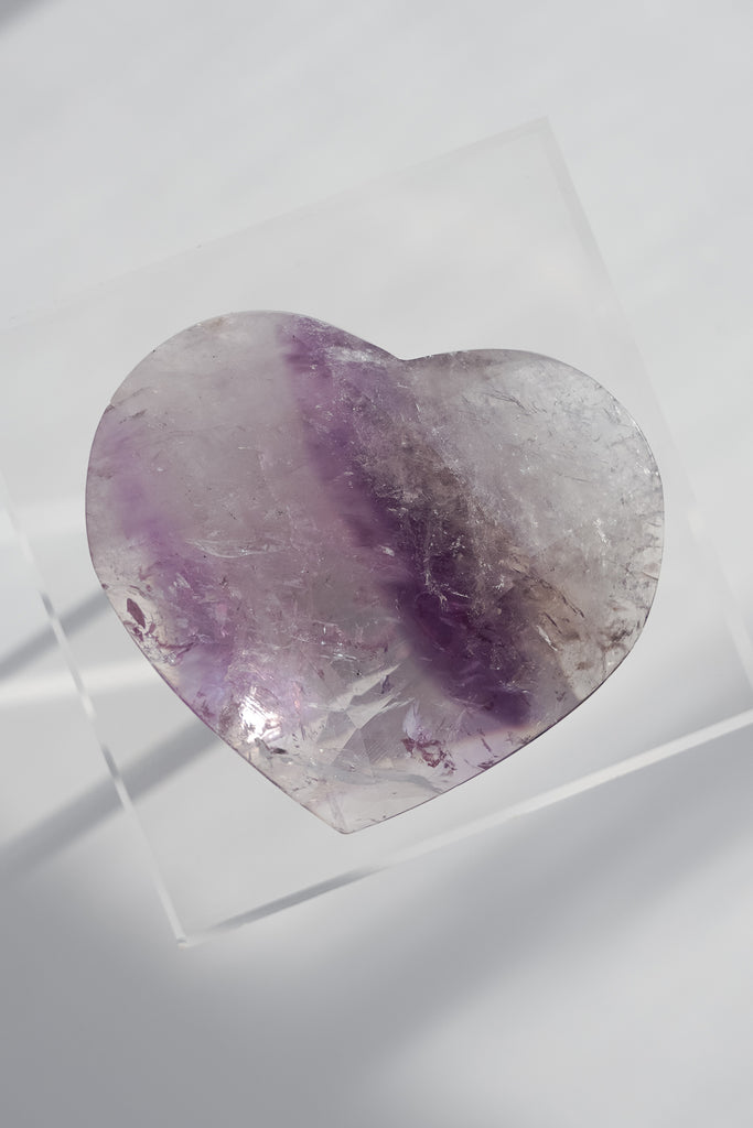 Heart-shaped amethyst crystal on a white background