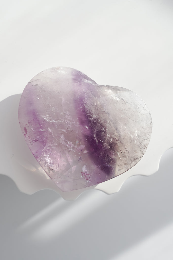 Heart-shaped crystal with purple and white colors on a white background