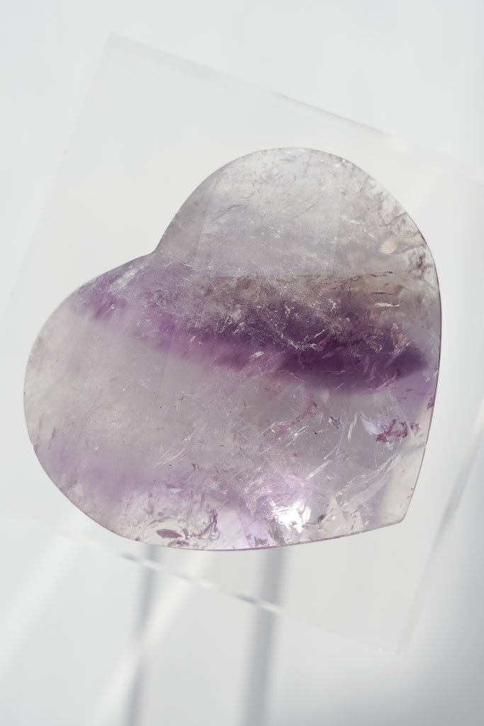 Heart-shaped amethyst crystal on a white background