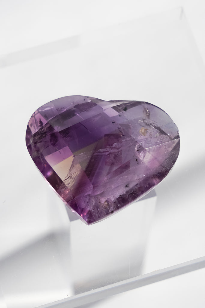 Heart-shaped purple gemstone on a white background