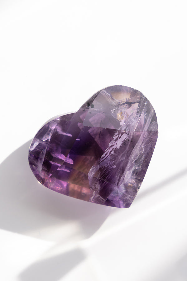 Heart-shaped purple gemstone on a white background