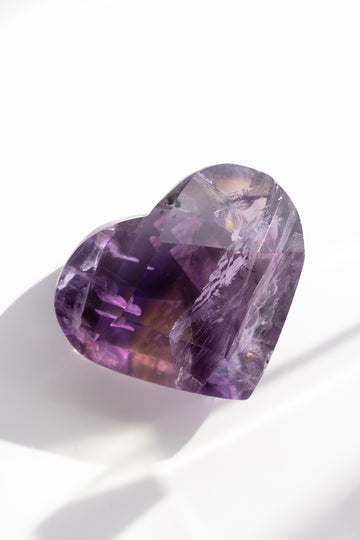 Heart-shaped purple gemstone on a white background