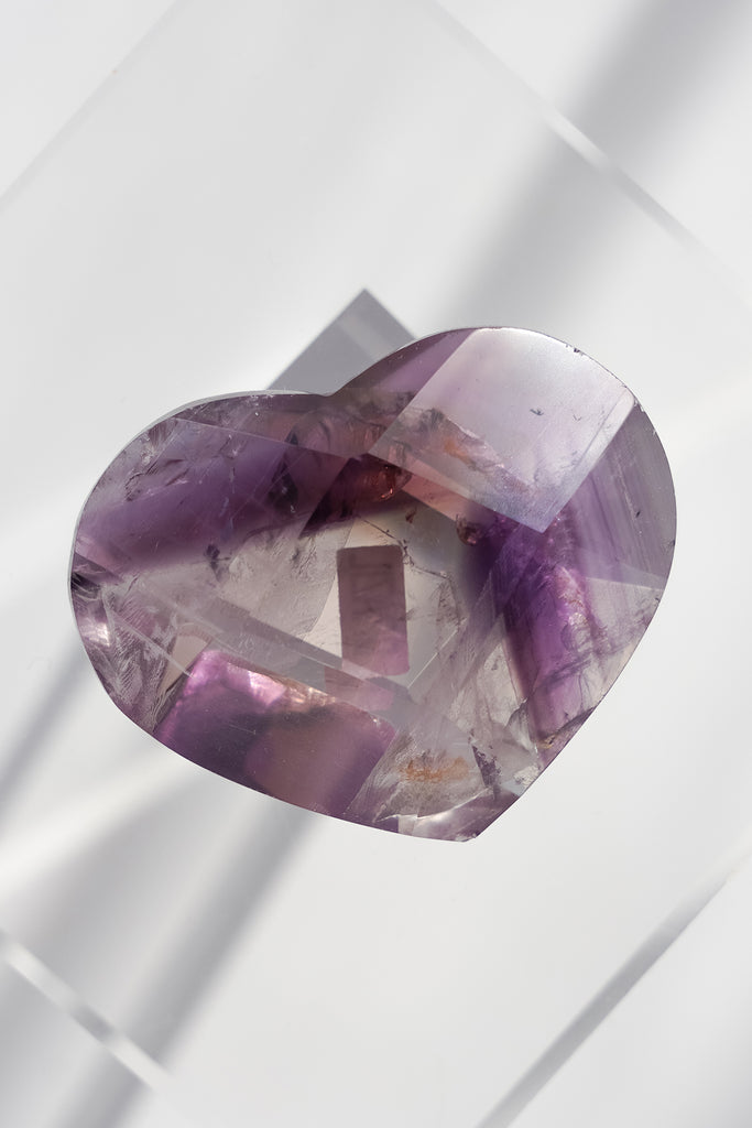 Heart-shaped purple crystal on a white geometric background