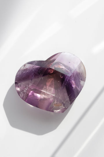 Heart-shaped purple gemstone on a white background