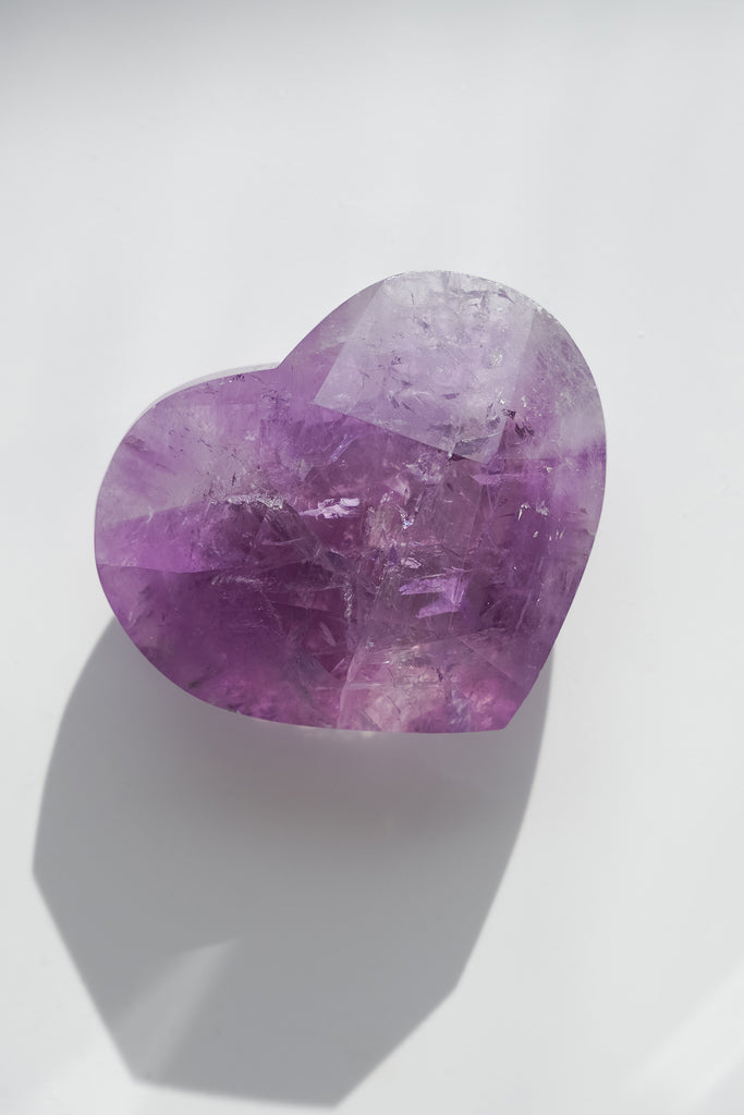 Heart-shaped purple crystal on a white background