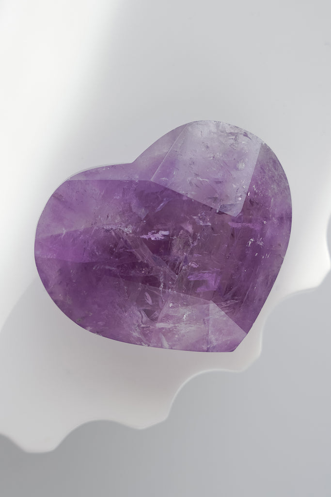 Heart-shaped purple crystal on a white background