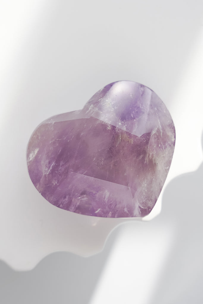 Heart-shaped purple crystal on a white background