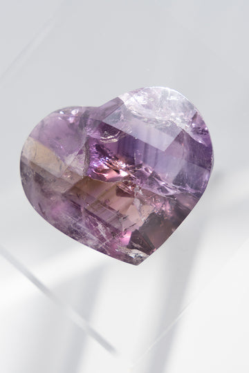 Heart-shaped purple gemstone on a light gray background
