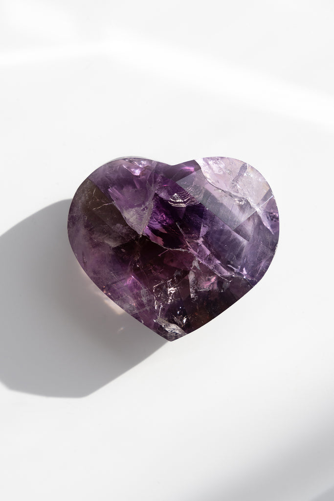 Heart-shaped purple crystal on a white background