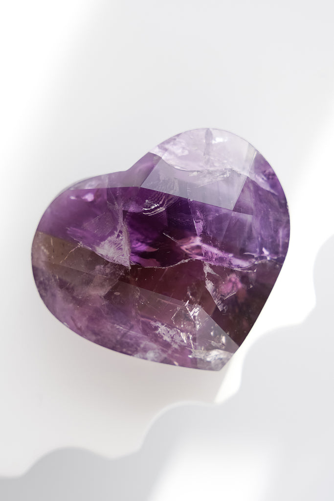 Heart-shaped purple crystal on a white background
