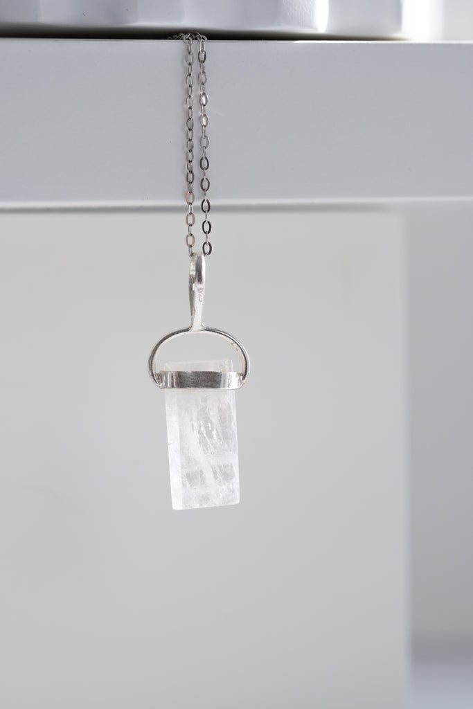 Crystal pendant on a chain against a white background