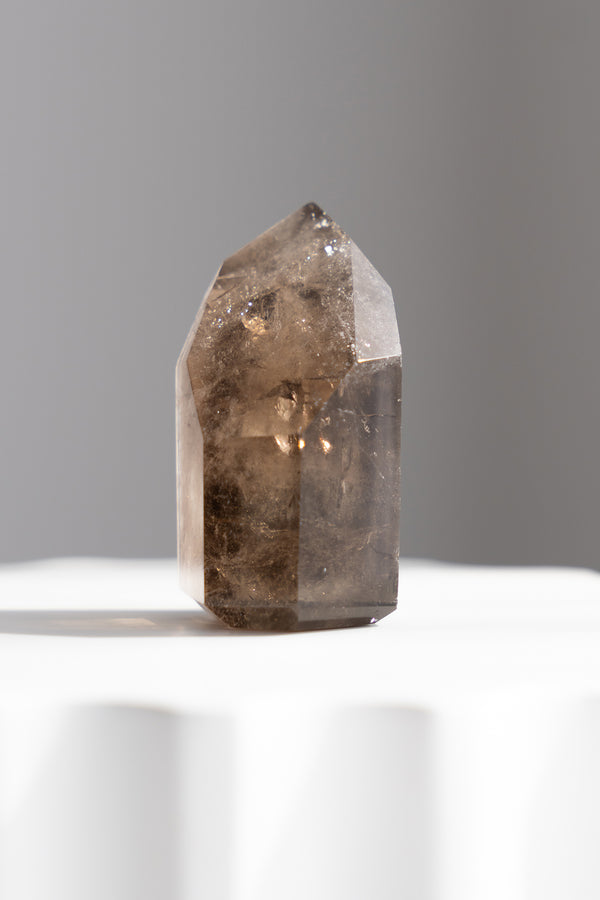 Smoky crystal on a white surface with a gray background