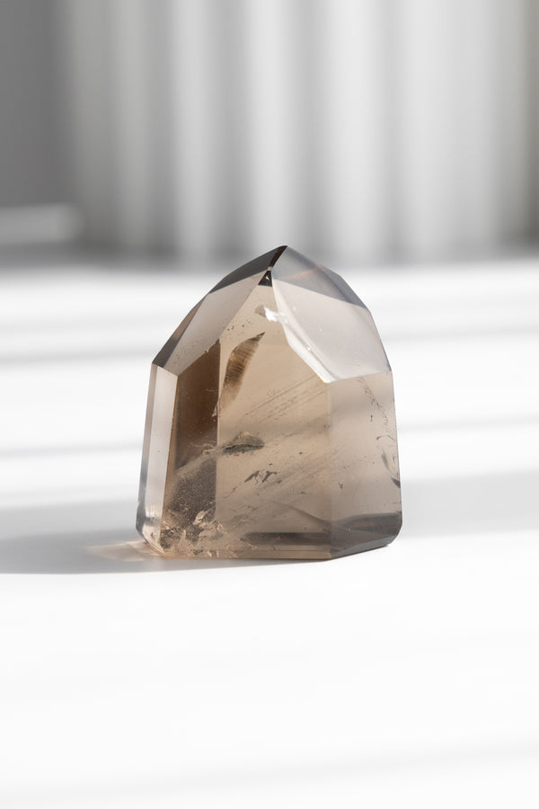 Smoky quartz crystal on a white surface with a neutral background