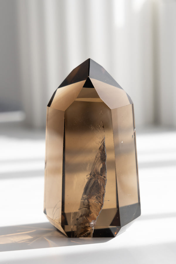 Smoky crystal on a white surface with a blurred background